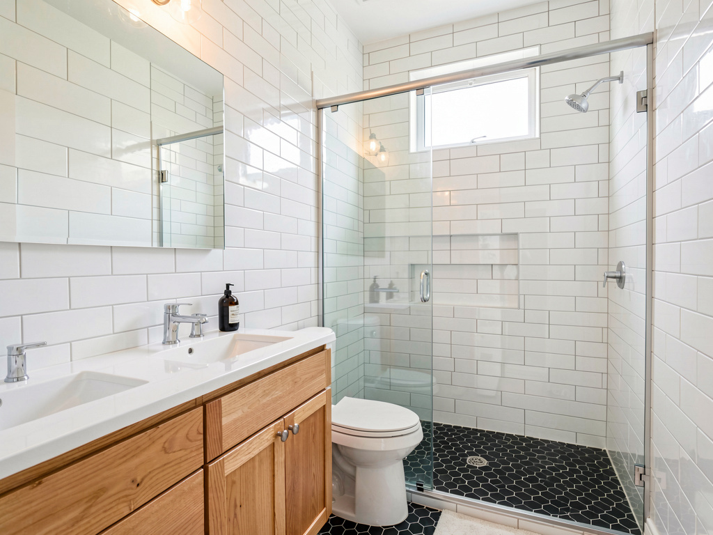 Bathroom with new white subway tile walls and black hexagonal floor tile, existing vanity and fixtures