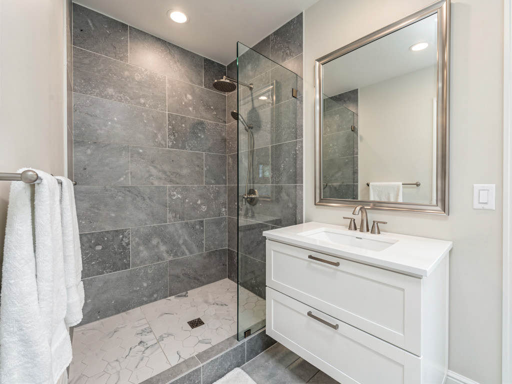 A completed bathroom renovation with walk-in shower, new vanity, and hexagonal floor tile