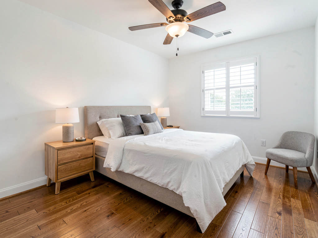 A master bedroom in a completed house flip staged with clean, modern furnishings for listing photos