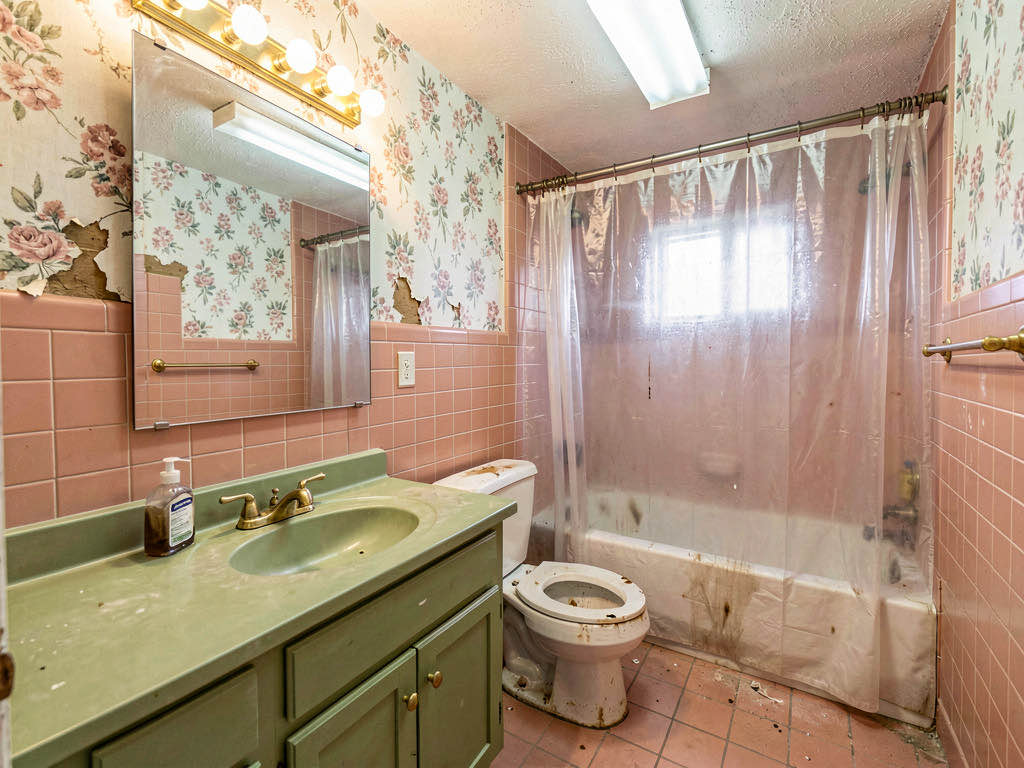 A dated bathroom with salmon pink tile and avocado green vanity before renovation