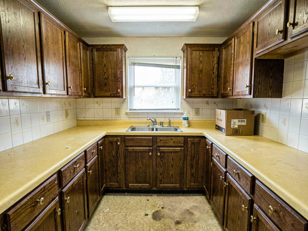 A dated kitchen with dark oak cabinets and laminate countertops ready for a flip renovation