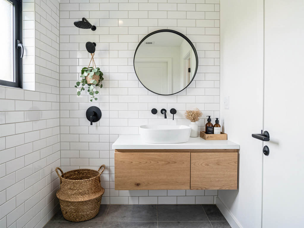 A small bathroom redesigned in spa style with white subway tile, floating oak vanity, and matte black fixtures
