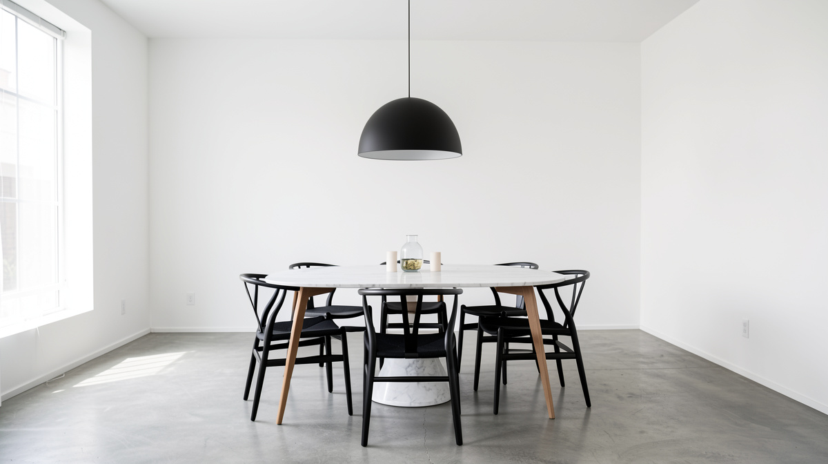 Modern dining room with oval marble table, sculptural chairs, linear pendant, and minimal decor