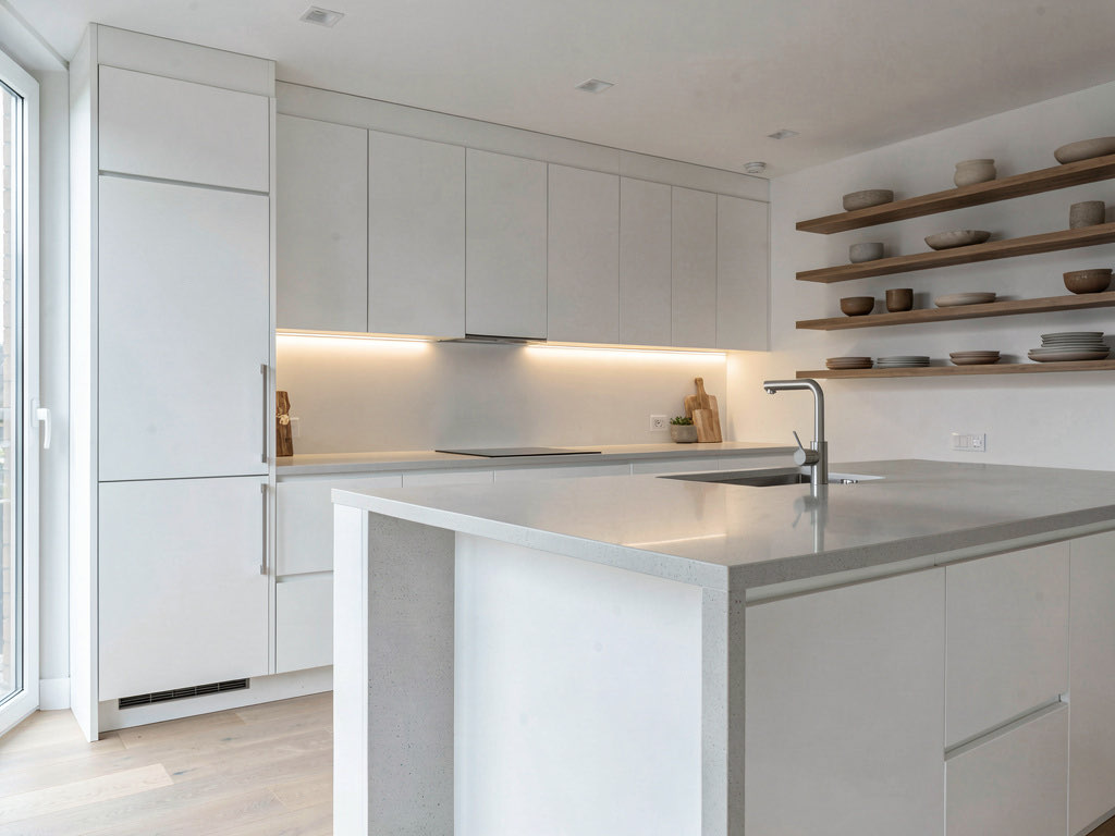 A kitchen redesigned in sleek modern style with flat-panel white cabinets, quartz island, and under-cabinet LED lighting
