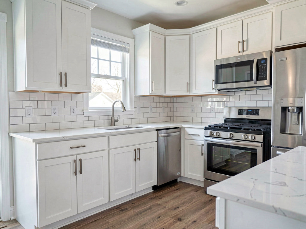A minor kitchen remodel with cabinets painted white, new quartz countertops, subway tile backsplash, stainless appliances, and new brushed nickel hardware