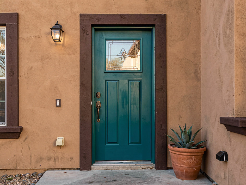 Teal blue-green front door on a tan stucco house with oil-rubbed bronze hardware