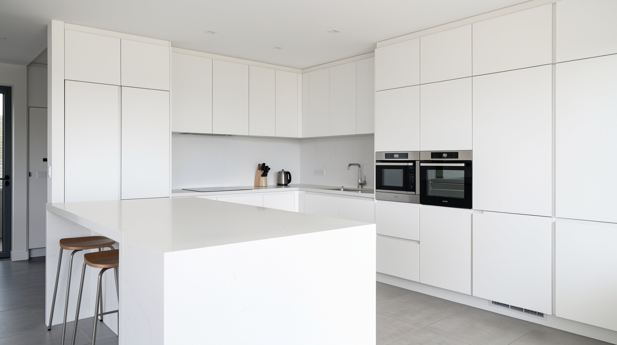 Modern kitchen with flat-panel wood cabinets, waterfall island, integrated appliances and pendant lights