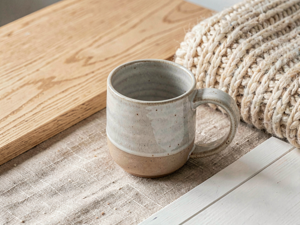 Close-up of Scandinavian design materials — light oak, linen fabric, ceramic, and wool textures